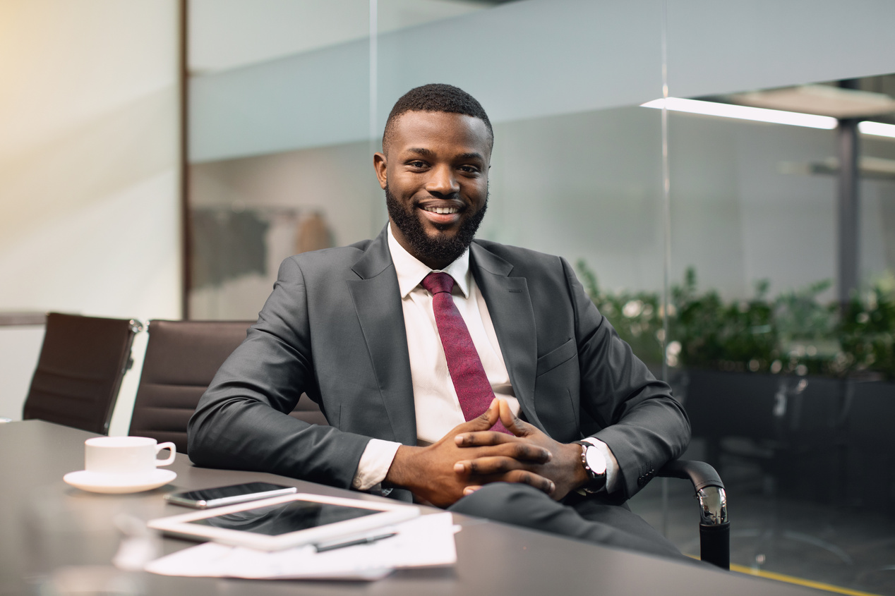 Cheerful Black Guy CEO Sitting at Conference Hall